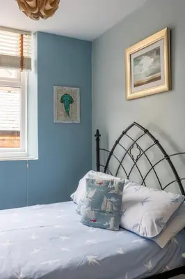 a bedroom with a bed with blue walls at Beach Snug in Lytham St Annes