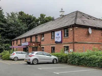 two cars parked in a parking lot in front of a brick building at Plaza Hotel, Preston Lancashire, Sure Collection by Best Western in Chorley