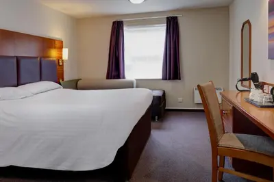 a hotel room with a large bed and a desk at Plaza Hotel, Preston Lancashire, Sure Collection by Best Western in Chorley