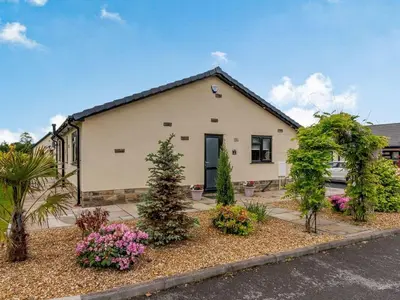 a house with trees and flowers in front of it at Beeches Cottage in Blackburn