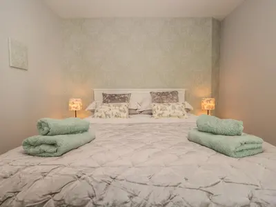 a bedroom with a large bed with two green pillows at Woodland Lodge in Grange Over Sands