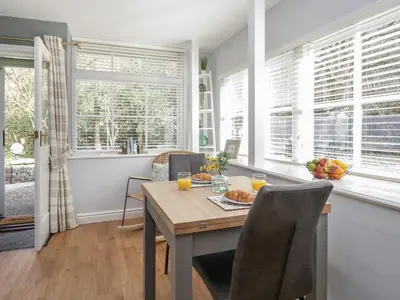a dining room with a table and chairs and windows at Woodland Lodge in Grange Over Sands
