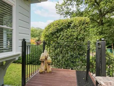 a black fence with two wooden statues on a porch at Woodland Lodge in Grange Over Sands