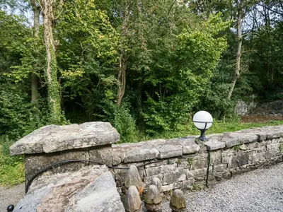 a stone wall with a light on top of it at Woodland Lodge in Grange Over Sands