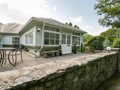 a house with a retaining wall and a patio at Woodland Lodge in Grange Over Sands