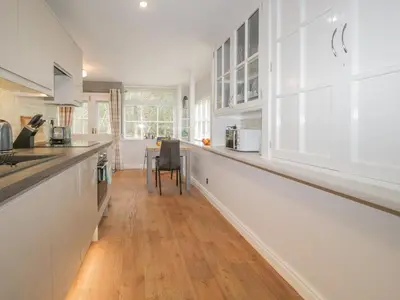 a kitchen with white cabinets and a long counter at Woodland Lodge in Grange Over Sands