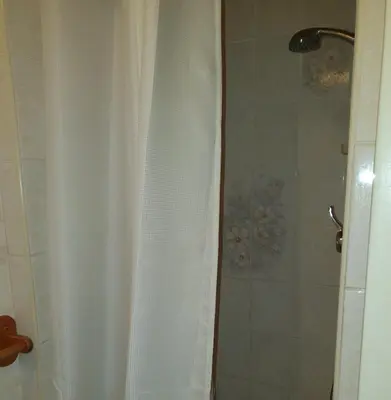 a shower with a white shower curtain in a bathroom at The Rutlands in Blackpool