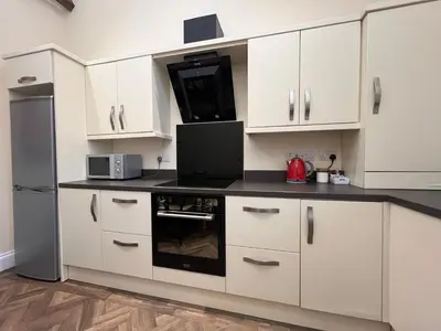 a kitchen with white cabinets and a black stove top oven at Innkeepers Cottage in Ulverston