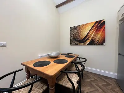 a dining room table with chairs and a painting on the wall at Innkeepers Cottage in Ulverston