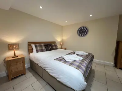 a bedroom with a bed and a clock on the wall at Innkeepers Cottage in Ulverston