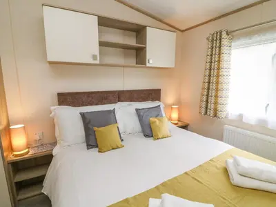 a bedroom with a large white bed with yellow pillows at 12A Borwick Lakes in Carnforth