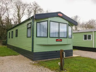 a green tiny house sitting on the grass at 12A Borwick Lakes in Carnforth