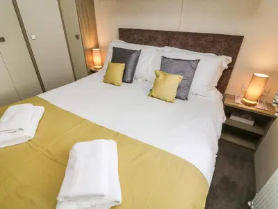 a bedroom with a large bed with yellow and grey pillows at 12A Borwick Lakes in Carnforth