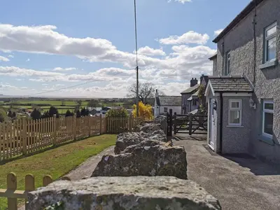 a house with rocks in front of a fence at Hillside Farm Cottage in Grange Over Sands