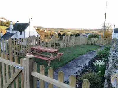 a wooden fence with a picnic table in a yard at Hillside Farm Cottage in Grange Over Sands