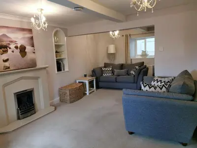 a living room with a blue couch and a fireplace at Hillside Farm Cottage in Grange Over Sands