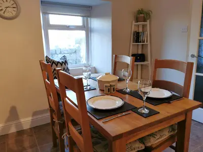 a dining room table with plates and glasses on it at Hillside Farm Cottage in Grange Over Sands