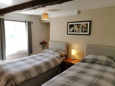 two beds in a room with a window at Hillside Farm Cottage in Grange Over Sands