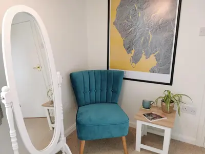 a blue chair sitting next to a mirror at Hillside Farm Cottage in Grange Over Sands
