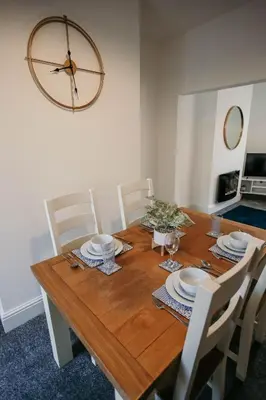 a wooden table with chairs and a large clock on the wall at PARKER St by Prestige Properties SA in Barrow in Furness