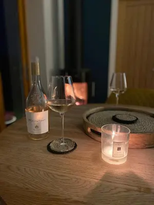 a bottle of wine and two glasses on a wooden table at Sawley in the Forest of Bowland - cosy cottage. in Clitheroe