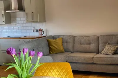 a living room with a couch and a vase with purple flowers at Sawley in the Forest of Bowland - cosy cottage. in Clitheroe