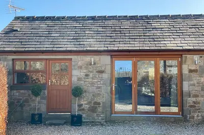 a stone house with a wooden door and windows at Sawley in the Forest of Bowland - cosy cottage. in Clitheroe