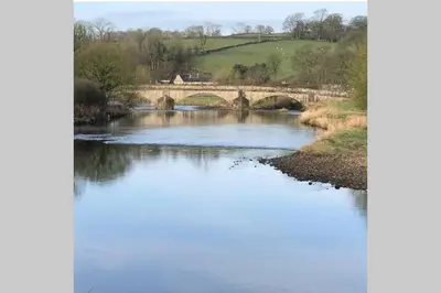 a river with a bridge in the background at Sawley in the Forest of Bowland - cosy cottage. in Clitheroe