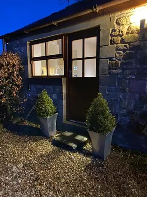 a house with two potted plants in front of a door at Sawley in the Forest of Bowland - cosy cottage. in Clitheroe