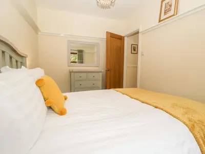 a bedroom with a white bed with a teddy bear on it at Laithe Cottage in Ulverston