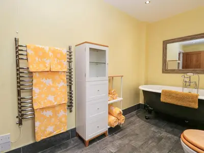 a bathroom with a bath tub and a sink at Laithe Cottage in Ulverston