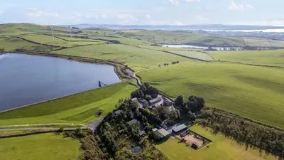an aerial view of a house in a field next to a lake at Laithe Cottage in Ulverston