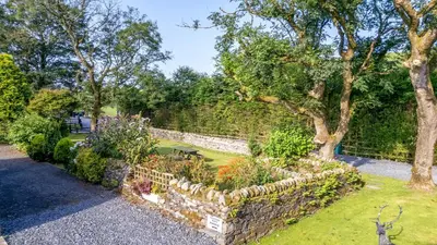 a garden with a stone wall and some plants at Laithe Cottage in Ulverston