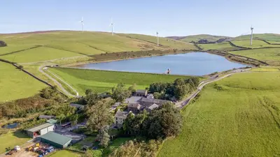an aerial view of a house in a field with a lake at Laithe Cottage in Ulverston