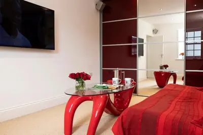 a room with a red table and a red bed at Finest Retreats - Lighthouse Cottage in Rampside