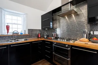 a kitchen with black cabinets and a sink at Finest Retreats - Lighthouse Cottage in Rampside