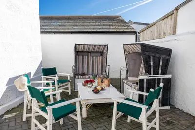 a patio with chairs and a table with flowers on it at Finest Retreats - Lighthouse Cottage in Rampside