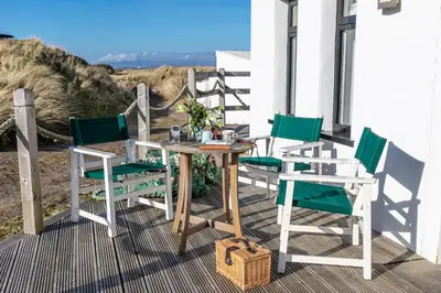 a table and four chairs on a porch with the beach at Finest Retreats - The Lighthouse Hide in Rampside