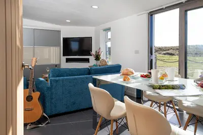 a living room with a blue couch and a table with a guitar at Finest Retreats - The Lighthouse Hide in Rampside