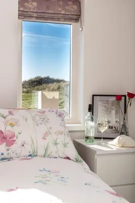 a bed with a pillow and a window with a glass of wine at Finest Retreats - The Lighthouse Hide in Rampside