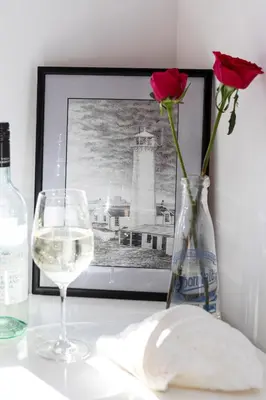 a bottle of wine and a vase with a rose and a glass at Finest Retreats - The Lighthouse Hide in Rampside