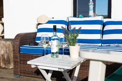 a table with two glasses of wine on a couch at Finest Retreats - The Lighthouse Hide in Rampside