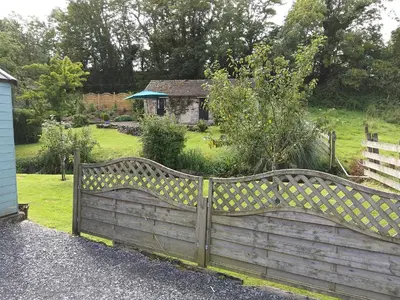 a wooden fence in front of a garden at Lile Cottage at Gleaston Water Mill in Ulverston