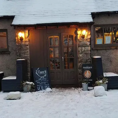 a restaurant in the snow with a sign in front of it at Lile Cottage at Gleaston Water Mill in Ulverston