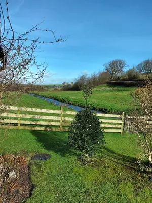 a fence in a field with a river in it at Lile Cottage at Gleaston Water Mill in Ulverston