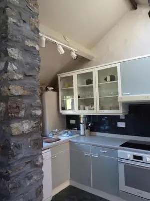 a kitchen with white cabinets and a stone wall at Lile Cottage at Gleaston Water Mill in Ulverston