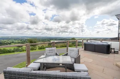a patio with couches and a table and a tv on a balcony at Valley View Lodge Sleeps 8 with Hot Tub in Preston