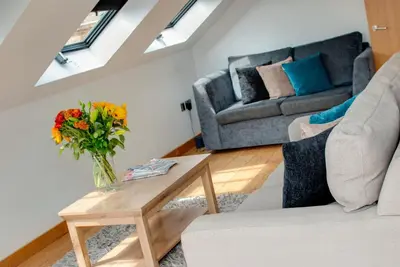 a living room with a couch and a table with a vase of flowers at Base Serviced Apartments - Sir Thomas Street in Liverpool