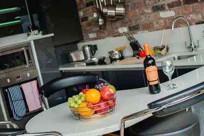 a bowl of fruit on a table with a bottle of wine at Base Serviced Apartments - Sir Thomas Street in Liverpool