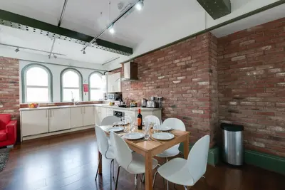 a kitchen with a table and chairs and a brick wall at Base Serviced Apartments - Sir Thomas Street in Liverpool